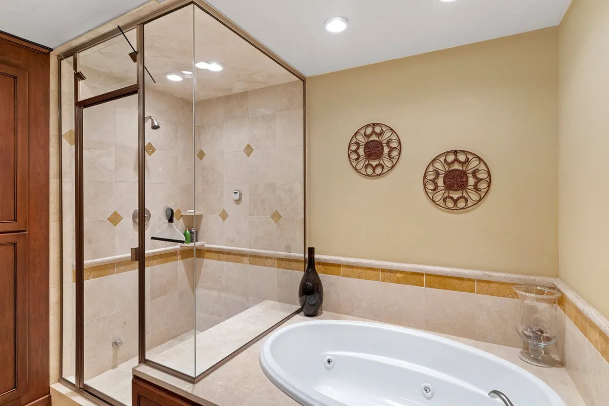 A luxurious bathroom featuring a glass-enclosed shower, a freestanding bathtub, decorative wall art, and a vase. The space feels serene and spa-like, with modern finishes and a calming palette ideal for relaxation and self-care.