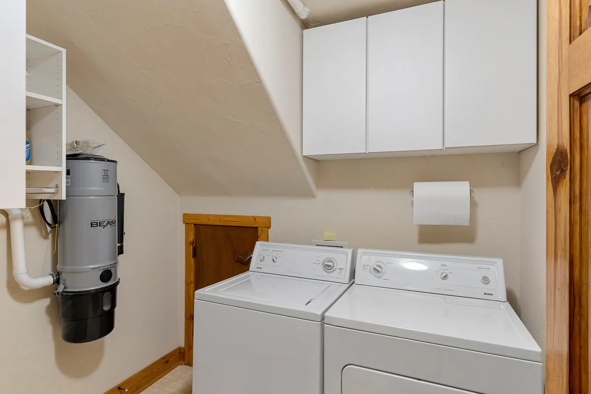A tidy laundry room equipped with a washer and dryer, ample storage cabinets, and a central vacuum system. The space is well-organized, bright, and highly functional—ideal for accommodating large groups and long stays.