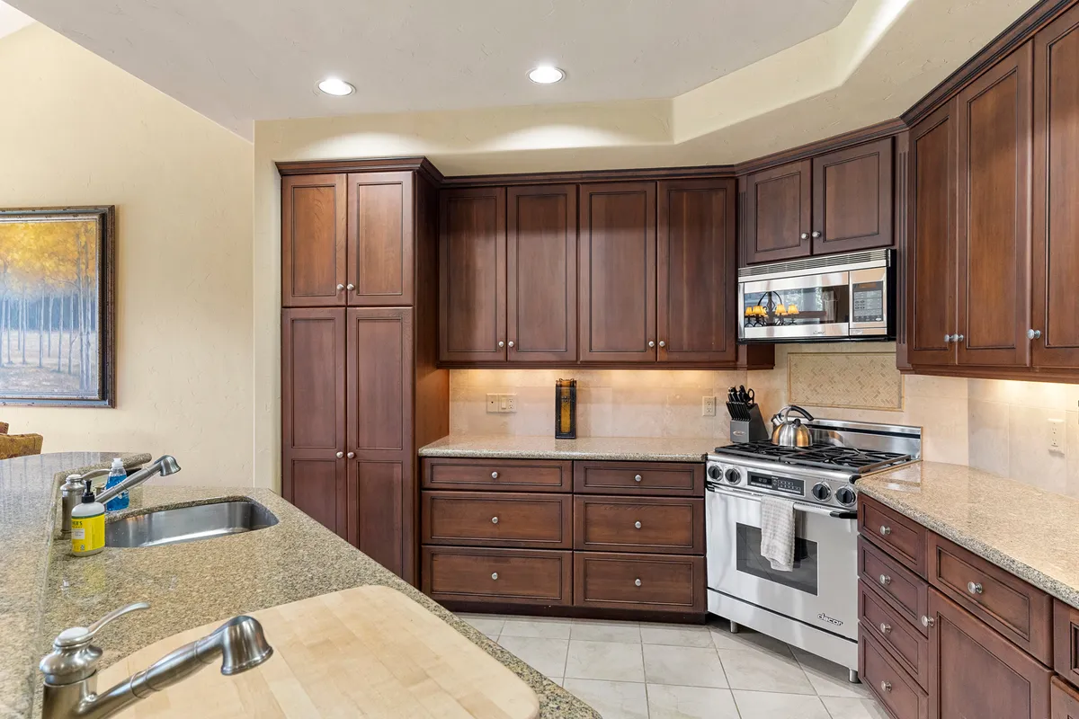 A modern kitchen with granite countertops, stainless steel appliances, rich wood cabinetry, and a kitchen sink. Bright and welcoming, the kitchen is designed for group cooking, entertaining, and casual dining.