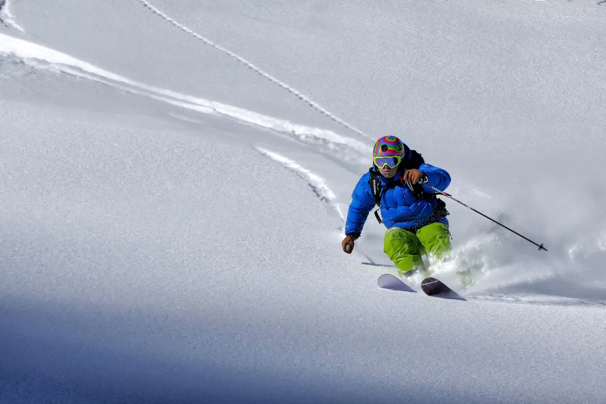 A skier captures the exhilaration of Steamboat’s legendary winter as they glide through untouched powder on a snow-covered mountain. The expansive mountain landscape is blanketed in white, emphasizing the thrill of outdoor winter activities.